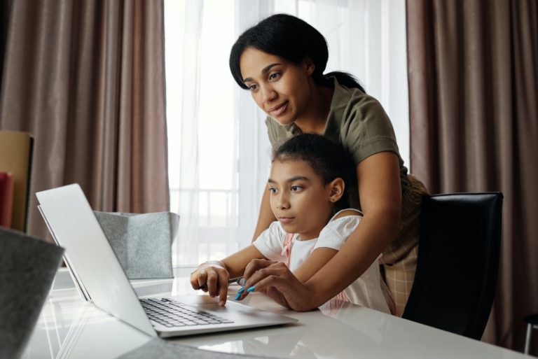 mother helping her child with using a laptop computer