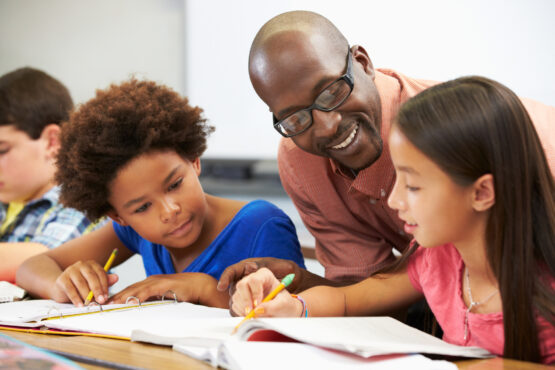 Teacher Helping Pupils Study In The Classroom